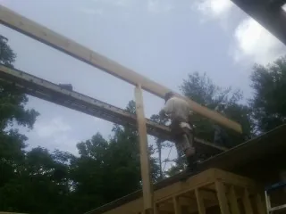 Carpenter setting a ridge beam over a new addition frame — Ice Dam Removal by Roofing Brothers in Kerkhoven