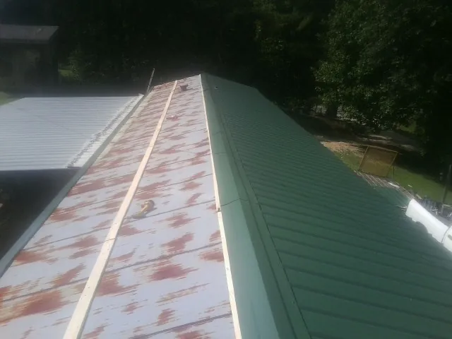 Old rusted panels beside newly installed green metal roofing — Wind Damage Roof Repair by Roofing Brothers in Kerkhoven