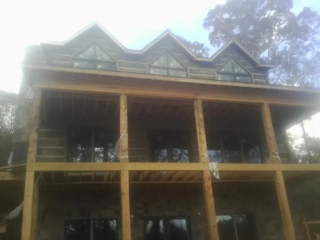 Dormers and porch framing on a large log home under construction — Roof Coating work by our crew in Kerkhoven