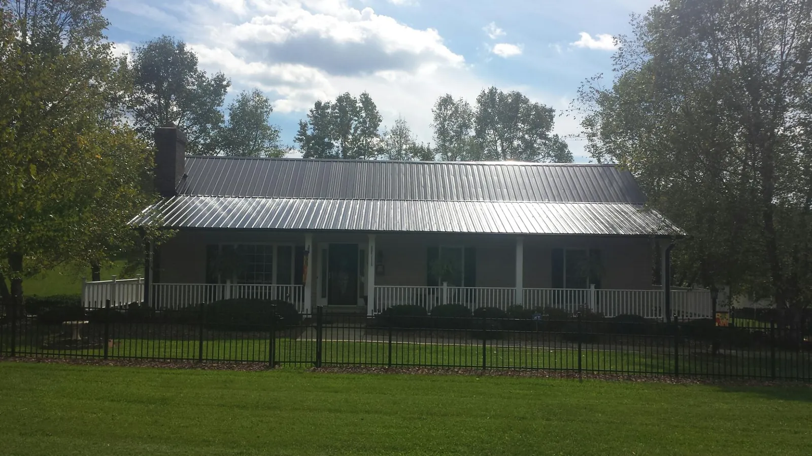 Gray metal roof on a brick ranch with a full width front porch — Gutter Guard Installation work by our crew in Kerkhoven