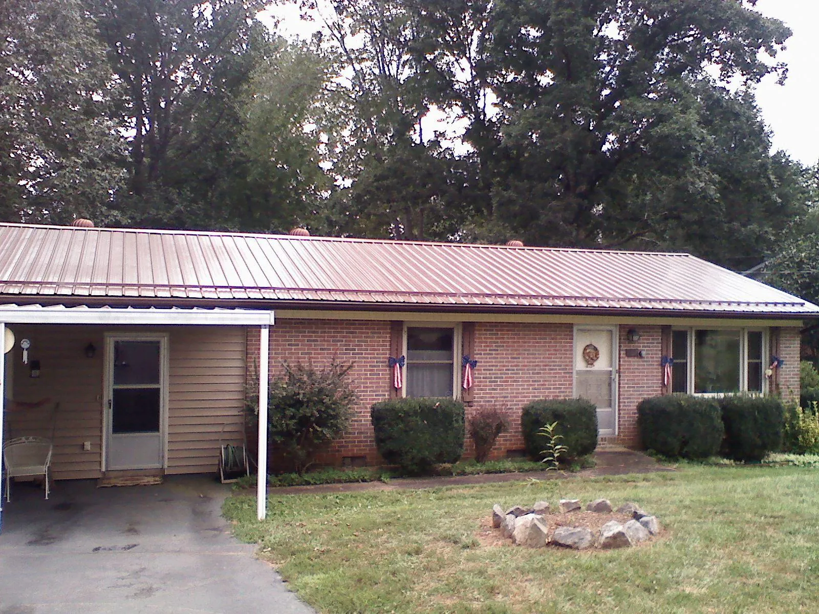 Bronze metal roof and carport on a brick ranch home — Roof Repair work by our crew in Kerkhoven