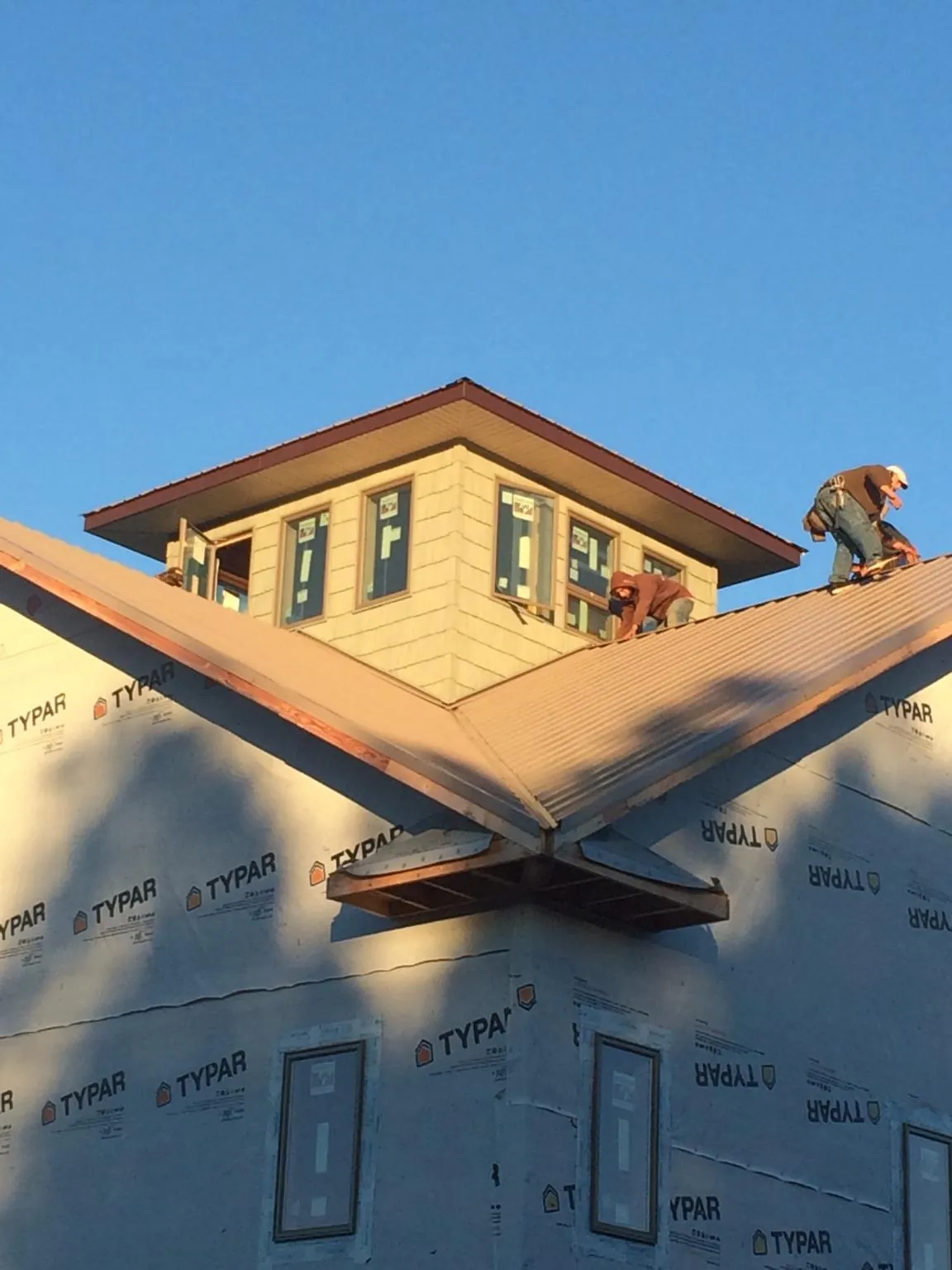 Roofers working around a rooftop cupola on a new metal roof at sunset — Roof Waterproofing in Kerkhoven by Roofing Brothers